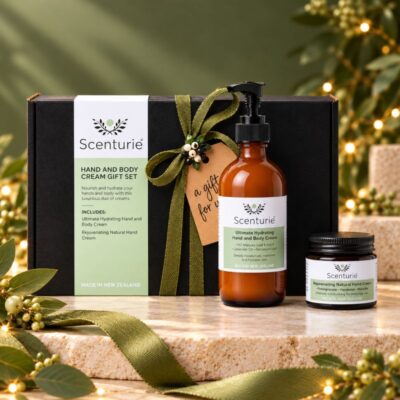 Scenturie Hand and Body Cream Gift Set with hydrating body cream and natural hand cream in amber bottles and a black gift box decorated with an olive-green Christmas ribbon.