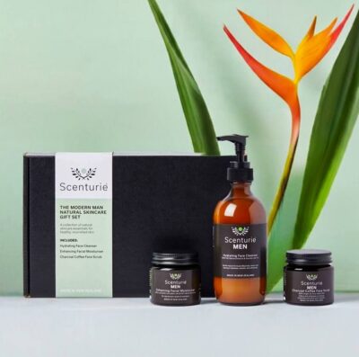 Scenturie Modern Man Natural Skincare Gift Set featuring the full-sized Cleanser, Scrub, and Moisturiser in front of a premium black gift box with a Bird of Paradise plant in the background.