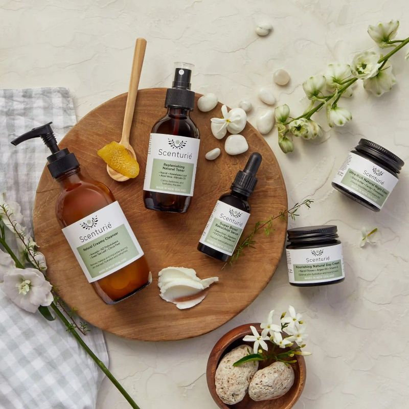 Scenturie amber glass skincare jars and bottles arranged in the Auckland studio alongside raw New Zealand botanical ingredients.
